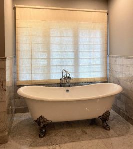 window shades in bathroom with clawfoot bathtub