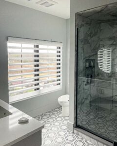 white marble bathroom with privacy shades and automated remote