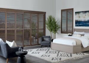 brown plantation shutters in bedroom on windows and patio doors with open louvers