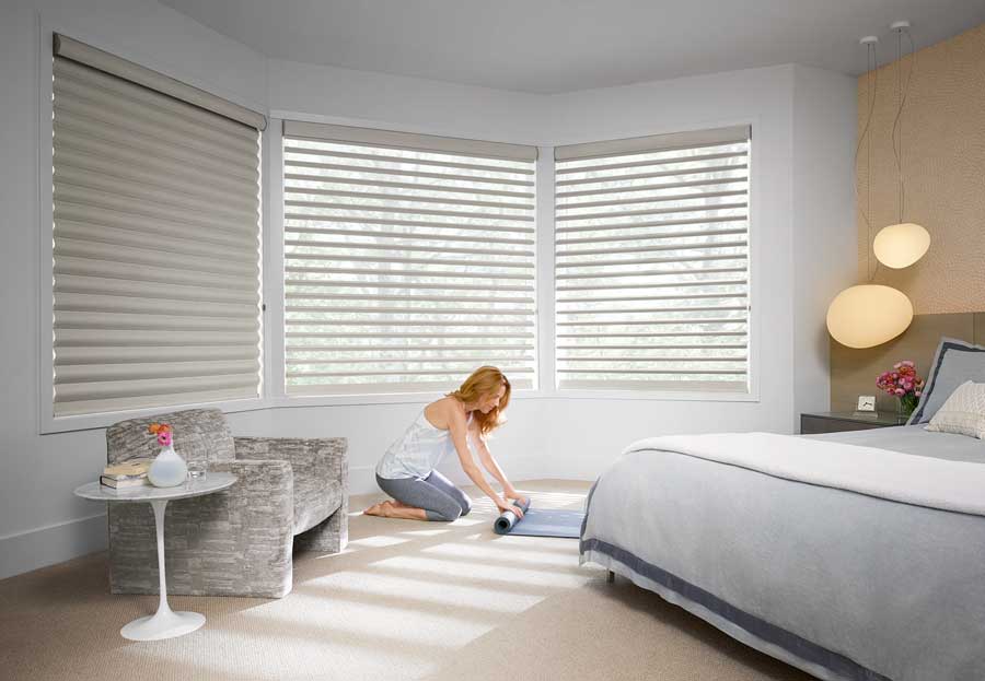 woman rolling up yoga mat next to pirouette window shades