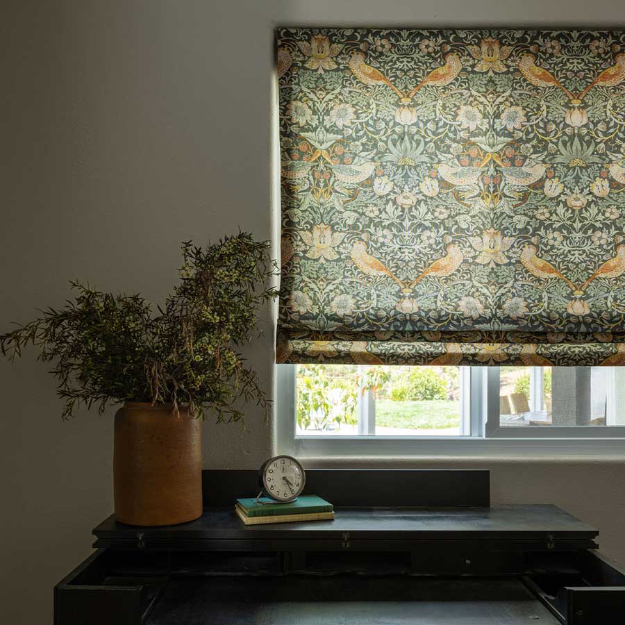 Custom Roman Shades in a pattern covering three fourths of a window behind a desk
