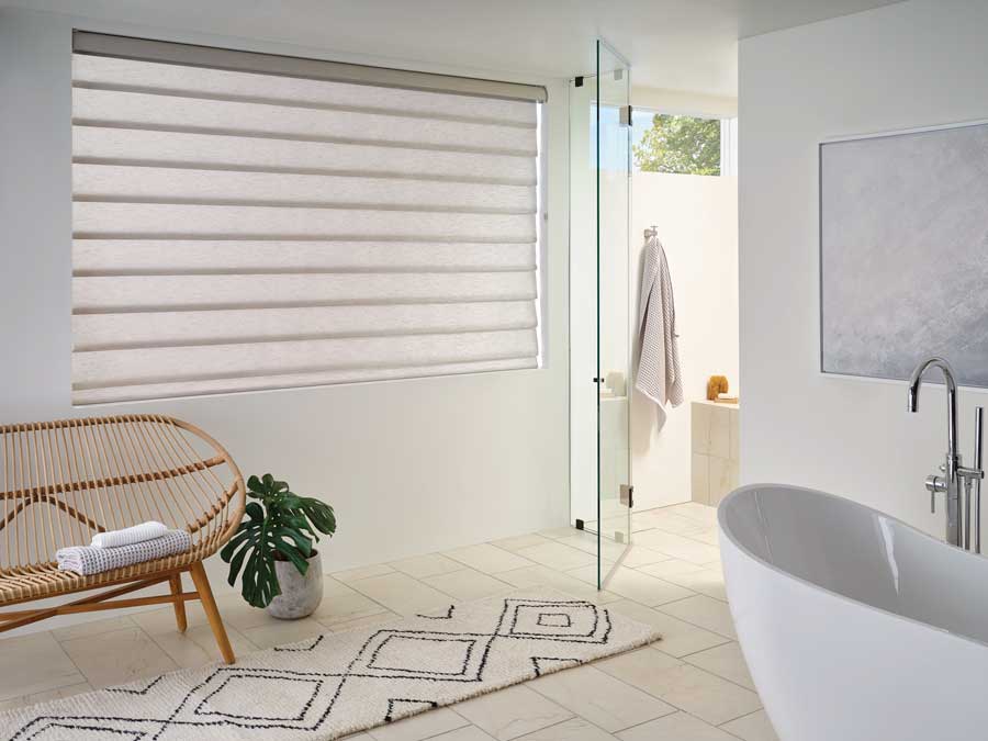 bathroom with large window near bathtub with bench vignette rolling roman shades
