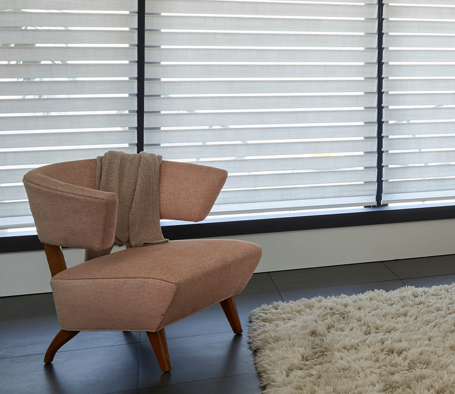 Horizontal fabric vanes of Silhouette window shades controlling light and privacy behind a mid-century style accent chair